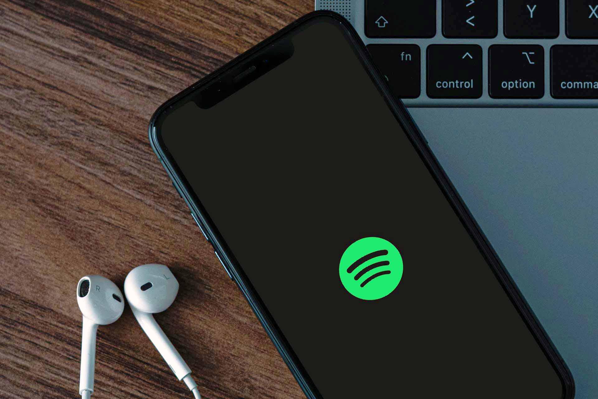 Un telefono con la app de Spotify sobre una laptop